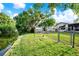 Landscaped backyard bordering a canal, featuring a wooden bird house and secure fencing at 10407 Oleander Dr, Port Richey, FL 34668
