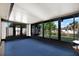 Enclosed sun room with large windows and blue carpet flooring provides a relaxing space to enjoy the outdoors from inside at 10407 Oleander Dr, Port Richey, FL 34668
