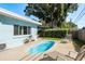 Lush backyard showcasing a shimmering pool, lounging chairs, and mature trees at 1281 Robin Hood Ln, Dunedin, FL 34698