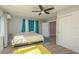 Bedroom features wood-look floors, ceiling fan, and curtains that frame the light from the large windows at 1281 Robin Hood Ln, Dunedin, FL 34698