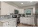 Well-lit kitchen with stainless steel appliances, subway tile backsplash, and white cabinetry at 1281 Robin Hood Ln, Dunedin, FL 34698