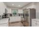 Updated kitchen features stainless steel appliances, white cabinets, tile backsplash, and wood-look floors at 1281 Robin Hood Ln, Dunedin, FL 34698