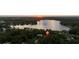 Stunning aerial view of lakefront property at sunset, nestled among trees with peaceful water at 14449 Wadsworth Dr, Odessa, FL 33556