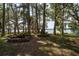 Lakeside backyard featuring a fire pit and mature trees, providing a relaxing waterfront atmosphere at 14449 Wadsworth Dr, Odessa, FL 33556