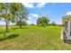 Backyard view of a large, green lawn under a blue sky, a nearby patio, and many large trees at 1609 Pebble Beach N Blvd, Sun City Center, FL 33573