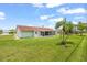 Backyard view of a white home with a red roof, green lawn, and a screened-in porch under a blue sky at 1609 Pebble Beach N Blvd, Sun City Center, FL 33573