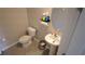 Cozy powder room features a pedestal sink and toilet with cleaning supplies and updated gray tile at 16728 Kingman Reef St, Wimauma, FL 33598