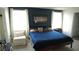 A spacious bedroom boasts a cozy bed, natural light from two windows, and serene blue accent wall at 16728 Kingman Reef St, Wimauma, FL 33598