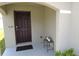 Inviting covered front porch with a dark wooden door and neutral-colored walls at 16728 Kingman Reef St, Wimauma, FL 33598