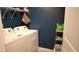 Functional laundry area with modern white washer and dryer, shelving, and a laundry basket at 16728 Kingman Reef St, Wimauma, FL 33598
