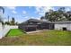 Backyard featuring a screened-in pool area, artificial turf, and lush greenery at 1675 Eden Ct, Clearwater, FL 33756