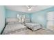 Cozy bedroom showcasing two twin beds, neutral carpet, ceiling fan, and well-lit window overlooking the yard at 1675 Eden Ct, Clearwater, FL 33756