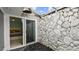 Idyllic courtyard showing the rock floor, stone wall, and entry to an interior bedroom with sliding glass door at 1675 Eden Ct, Clearwater, FL 33756