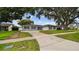 Inviting single-story home with a concrete driveway, lush lawn, and mature trees offering shade at 1675 Eden Ct, Clearwater, FL 33756