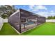 A swimming pool in a screened-in enclosure in the backyard with artificial turf on the side at 1675 Eden Ct, Clearwater, FL 33756