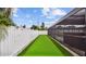 A backyard with artificial turf next to a screened-in pool and privacy fence at 1675 Eden Ct, Clearwater, FL 33756