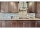 Gourmet kitchen featuring granite countertops, stainless steel hood, and stylish tile backsplash at 1821 Cherry Walk Rd, Lutz, FL 33558