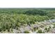 Aerial view of houses in a community bordering a forest, some homes with private pools, and water in the distance at 18343 Waydale Loop, Hudson, FL 34667