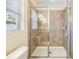 Modern bathroom featuring a glass shower with neutral tile, bright lighting, and a window for natural light at 18343 Waydale Loop, Hudson, FL 34667