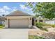 Home featuring an attached two-car garage, concrete driveway, and lovely front yard landscaping at 18343 Waydale Loop, Hudson, FL 34667
