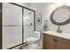 Bathroom featuring a glass-enclosed shower, toilet, vanity with sink, and a round mirror above the sink at 204 S Trask St, Tampa, FL 33609