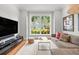 Living room with hardwood floors, a large window, a comfortable gray sofa and a flat screen television at 204 S Trask St, Tampa, FL 33609
