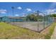 Community tennis court surrounded by lush landscaping and building in the background at 20921 Haulover Cv # 8, Lutz, FL 33558