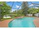 Sparkling pool featuring waterfall, within a screened lanai overlooking lake at 2238 Shirecrest Cove Way, Lutz, FL 33558