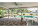 Screened-in outdoor patio features pool and a jacuzzi surrounded by a paved brick deck and manicured lawn at 22755 Cypress Trail Dr, Lutz, FL 33549