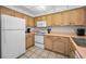 Well-lit kitchen featuring white appliances, and natural wood cabinets at 24 Gulf Blvd # 1C, Indian Rocks Beach, FL 33785