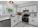 Bright kitchen features white cabinets, stainless steel appliances, quartz countertops, and marble floors at 2432 Keene Park Dr, Largo, FL 33771