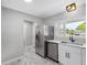 Stainless steel refrigerator stands next to sink with stainless steel appliances and marble floors at 2432 Keene Park Dr, Largo, FL 33771