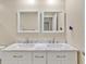Bathroom featuring dual sinks with marble countertop, modern fixtures, and well-lit mirrors at 25555 Oaks Blvd, Land O Lakes, FL 34639