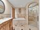 Luxurious bathroom featuring an elegant soaking tub, glass-enclosed shower, and ornate vanity with designer fixtures at 25555 Oaks Blvd, Land O Lakes, FL 34639