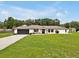 Inviting single-story home showcasing a dark garage door and a beautifully landscaped front yard with green grass at 25555 Oaks Blvd, Land O Lakes, FL 34639