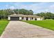 A single-story home with a long driveway, dark garage door, and well-maintained landscaping at 25555 Oaks Blvd, Land O Lakes, FL 34639