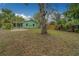 A large backyard with trees, grass, wooden fence and a green house with a covered patio at 2931 23Rd N St, St Petersburg, FL 33713