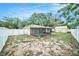 Backyard with a white fence and a view of the house with screened porch and shed at 3021 Jarvis St, Holiday, FL 34690