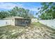 Backyard with a white fence and a view of the house with screened porch and shed at 3021 Jarvis St, Holiday, FL 34690