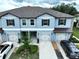 Aerial view of a two-story townhome showcases manicured landscaping and private garages at 30729 Veridian Way, Wesley Chapel, FL 33543