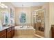 Luxurious bathroom featuring a soaking tub, granite countertops, chandelier lighting and a glass-enclosed shower at 3228 Stonegate Falls Dr, Land O Lakes, FL 34638