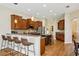 Modern kitchen with stainless steel appliances, granite countertops, wood cabinets and pendant lighting over breakfast bar at 3228 Stonegate Falls Dr, Land O Lakes, FL 34638