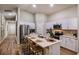 Modern kitchen features stainless steel appliances, white cabinetry, and an island with barstool seating at 36953 Sagemoor Dr, Zephyrhills, FL 33541