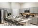Modern kitchen features stainless steel appliances, stylish gray cabinets, and a large island with barstool seating at 36995 Sagemoor Dr, Zephyrhills, FL 33541