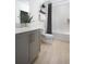 Modern bathroom with gray vanity, wood-look tile flooring, and tub with shower at 37029 Sagemoor Dr, Zephyrhills, FL 33541