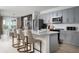 This open-concept kitchen features an island with bar seating, stainless appliances, and grey cabinets at 37029 Sagemoor Dr, Zephyrhills, FL 33541