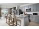 This open-concept kitchen features an island with bar seating, stainless appliances, and grey cabinets at 37029 Sagemoor Dr, Zephyrhills, FL 33541
