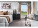 This bedroom features a white stone accent wall, plush bedding, and a view of green land through the window at 37029 Sagemoor Dr, Zephyrhills, FL 33541