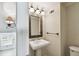 Cozy bathroom with a pedestal sink, decorative mirror and a wall sconce at 4506 La Capri Ct, Tampa, FL 33611