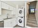 In-unit laundry setup with stacked washer/dryer and stairs, situated near stylish white cabinets at 4506 La Capri Ct, Tampa, FL 33611